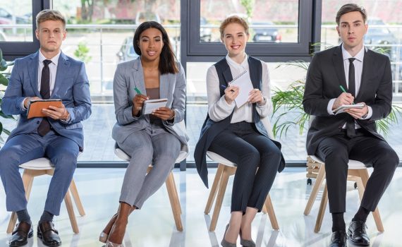 Businessmen and businesswomen with notepads listening to presentation in modern office